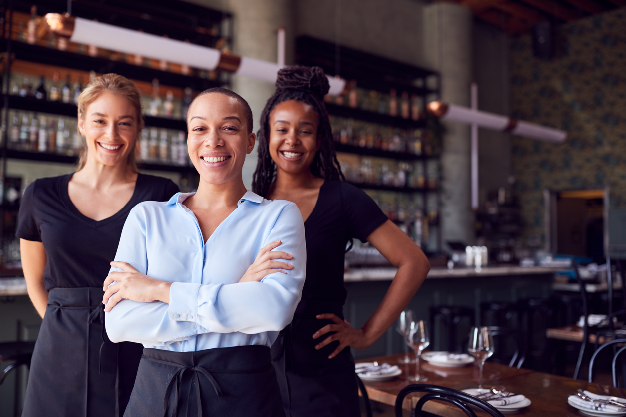 Portrait Of Female Owner Of Restaurant Bar With Team Of Waiting Staff Standing By Counter