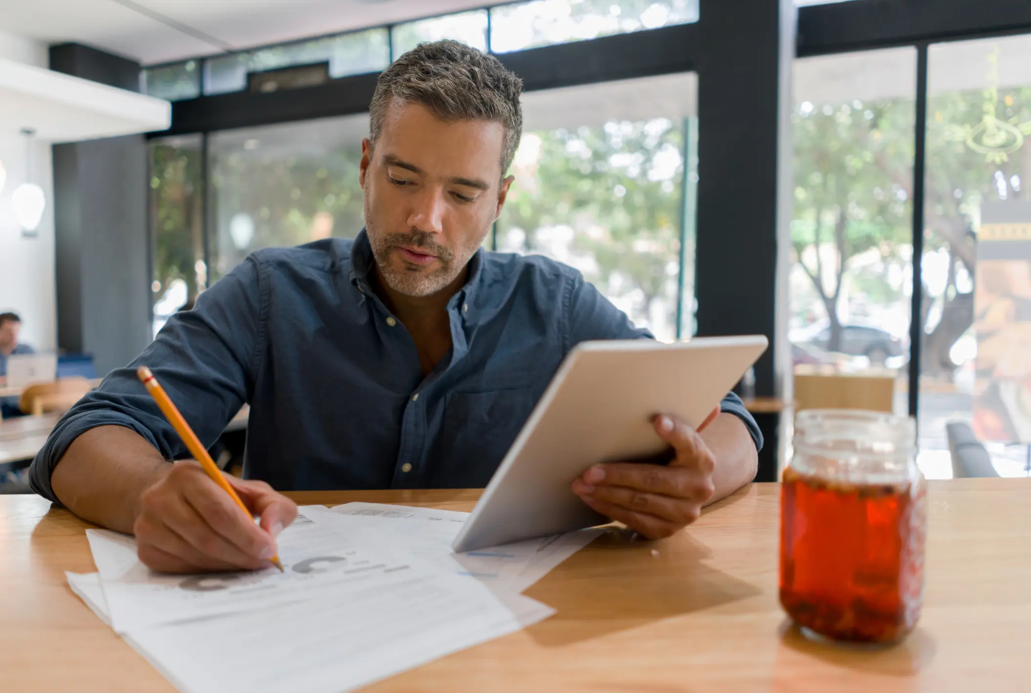 Man working at a cafe while drinking a cup of coffee